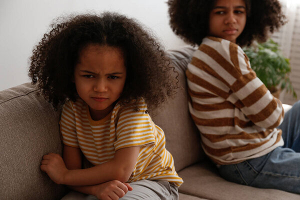 Younger and older sister in a state of emotional stress displeased with each other. Two black girls of different age arguing. Black female siblings having a fight. Background, copy space, close up.