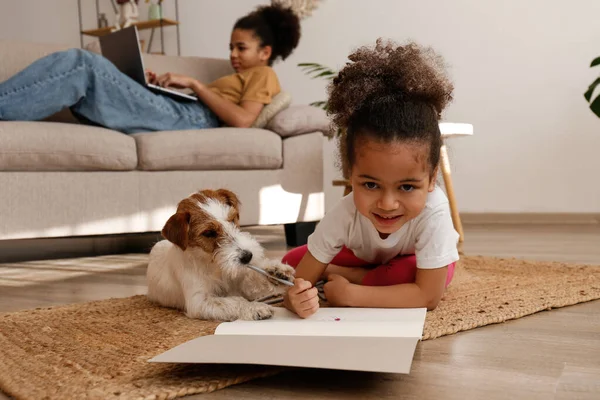 Farklı yaşlarda iki güzel siyah kız sevimli tel saçlı Jack Russel teriyerleriyle evde oynuyorlar. Sert kaplamalı sevimli kız kardeşler eğleniyor. Arkaplan, kapat, boşluğu kopyala.