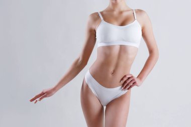 Beyaz arka planda izole edilmiş iç çamaşırlı, tanınmayan fit bir kadını yakından çek. Düz göbekli, beyaz iç çamaşırlı, zayıf, çekici bir kadın gövdesi. Metin için alanı kopyala.