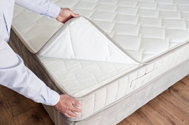 Cropped shot of man showcasing the waterproof topper for white orthopedic mattress. Male showing hypoallergenic foam matress protector. Close up, copy space, top view, background. clipart