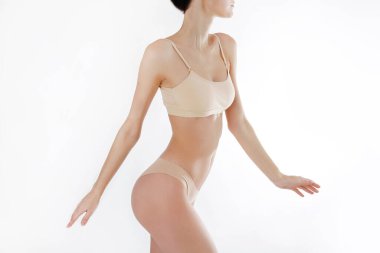 Beyaz arka planda izole edilmiş iç çamaşırlı, tanınmayan fit bir kadını yakından çek. Düz göbekli, beyaz iç çamaşırlı, zayıf, çekici bir kadın gövdesi. Metin için alanı kopyala.