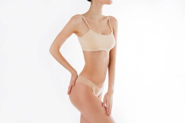 Beyaz arka planda izole edilmiş iç çamaşırlı, tanınmayan fit bir kadını yakından çek. Düz göbekli, beyaz iç çamaşırlı, zayıf, çekici bir kadın gövdesi. Metin için alanı kopyala.