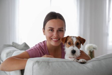 Genç ve güzel bir kadının portresi. Kanepede uzanmış. Tel saçlı Jack Russel teriyeri köpeğiyle. Sert kaplamalı sevimli kız eğleniyor. Arkaplan, kapat, boşluğu kopyala.