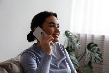 Beyaz gömlekli, telefonda konuşan ve gülümseyen esmer kadının portresi. Neşeli kadın model, eğlenceli bir telefon görüşmesi yapıyor. Arkaplan, kopyala boşluk, kapat.
