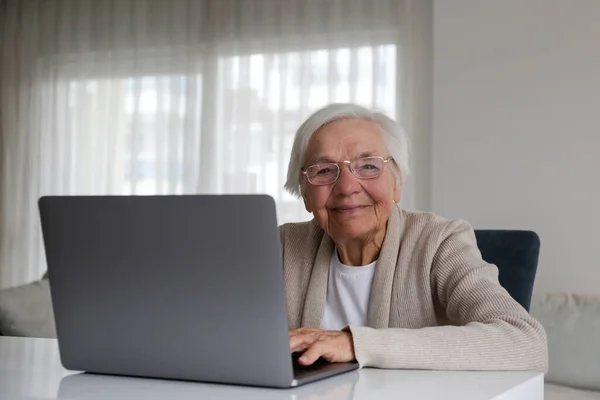 Portrait of elderly woman figuring out how to use a laptop. Older adult female learning about internet. Senior education. Digital health technology concept. Close up, copy space, background.