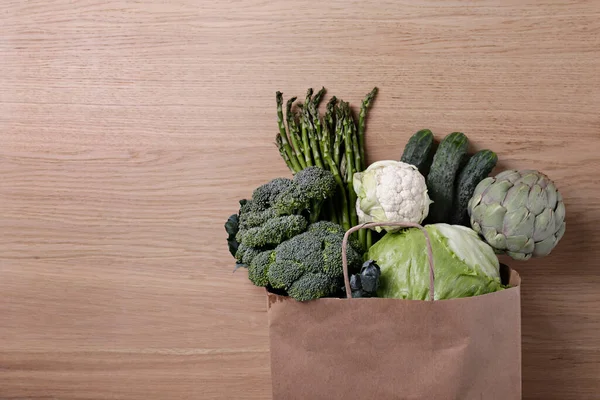 Bunch of mixed vegetables, herbs and greens in a brown paper bag. Vegan diet products. Clean eating concept. Eco friendly bag full of groceries. Close up, copy space, background, top view, overhead