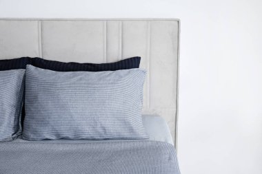 Hotel room with freshly made king sized bed with headboard, perfectly clean and ironed sheets, puffy pillows in natural sun light. Kingsize bed in a furniture showroom. Close up, copy space for text.