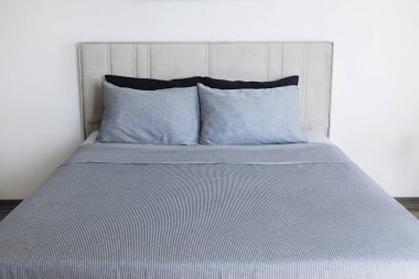 Hotel room with freshly made king sized bed with headboard, perfectly clean and ironed sheets, puffy pillows in natural sun light. Kingsize bed in a furniture showroom. Close up, copy space for text.