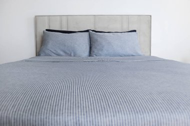 Yatak başlıklı, yeni yapılmış kral yataklı, temiz ve ütülenmiş çarşaflı, güneş ışığında şişkin yastıklı bir otel odası. Mobilya galerisinde büyük boy yatak. Kapat, metin için boşluk kopyala.