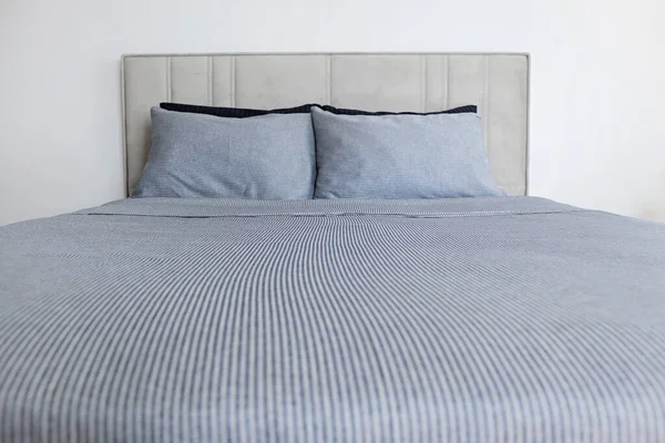 Hotel room with freshly made king sized bed with headboard, perfectly clean and ironed sheets, puffy pillows in natural sun light. Kingsize bed in a furniture showroom. Close up, copy space for text.