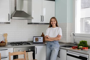 Genç ve güzel bir kadın mutfakta yalnız başına internetteki tarifi kullanarak salata pişiriyor. Vejetaryen yemeği için doğranmış kadın malzemesinin portresi. Kapat, kopyala boşluk, arkaplan.