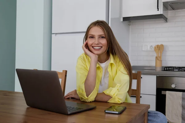 Genç Bir Kadının Dizüstü Bilgisayarla Uzaktan Çalışıp Mutfaktaki Masanın Başında — Stok fotoğraf