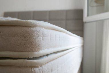 Queen sized bed with an orthopedic mattress in the bedroom. Hypoallergenic foam matress for proper spinal alignment and pressure point relief. Background, copy space, close up.