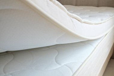 Queen sized bed with an orthopedic mattress in the bedroom. Hypoallergenic foam matress for proper spinal alignment and pressure point relief. Background, copy space, close up.