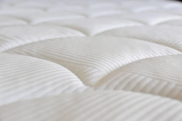 Close up shot of white orthopedic mattress top side surface pattern with a lot of copy space for text. Hypoallergenic foam matress for proper spinal alignment and pressure point relief. Background