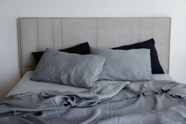 Room with an empty king sized bed with headboard, perfectly clean and ironed sheets, puffy pillows in natural sun light. Kingsize bed in a furniture showroom. Close up, copy space for text.
