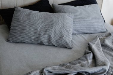 Room with an empty king sized bed with headboard, perfectly clean and ironed sheets, puffy pillows in natural sun light. Kingsize bed in a furniture showroom. Close up, copy space for text.