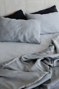 Room with an empty king sized bed with headboard, perfectly clean and ironed sheets, puffy pillows in natural sun light. Kingsize bed in a furniture showroom. Close up, copy space for text.