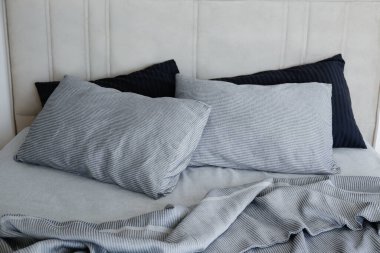 Room with an empty king sized bed with headboard, perfectly clean and ironed sheets, puffy pillows in natural sun light. Kingsize bed in a furniture showroom. Close up, copy space for text.