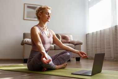 Çevrimiçi sınıfta yoga öğreten sportif yetişkin bir kadın. Ortaçağ Yogası 'na uygun canlı yayın Hatha yoga ana sınıfı. Ahşap zemin, arkaplan, kopyalama alanı, kapat.