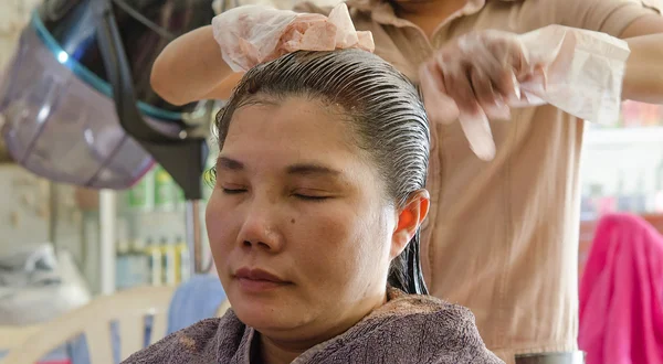 Esteticista aplicando tintura de cabelo no cabelo do cliente feminino — Fotografia de Stock