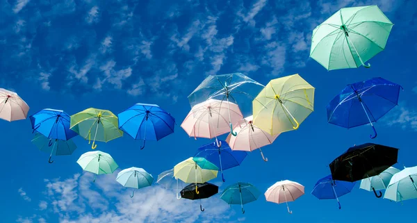 Guarda-chuvas multicoloridos contra fundo céu azul — Fotografia de Stock