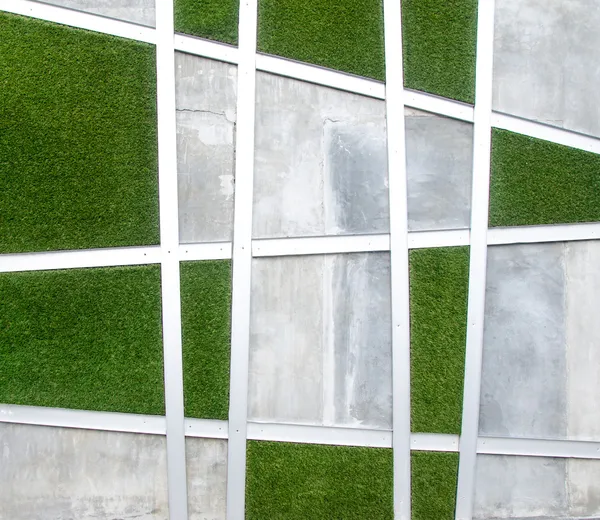 Цементная стена на фоне искусственной травы — стоковое фото