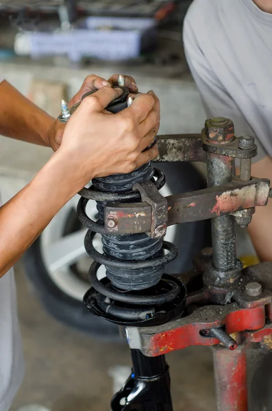 Auto car mechanic working on car shock absorber in car service w — Stock Photo, Image