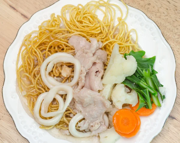 Crispy fried egg noodle with pork and squid and kale soaked in g — Stock Photo, Image