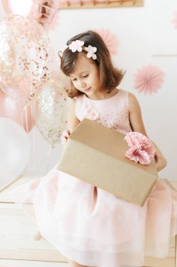 Altı yaşında açık pembe elbiseli bir kız evde doğum gününü kutluyor..