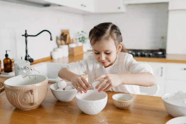 Little Caucasian brown-haired girl baking on white kitchen at home — Stock Photo, Image