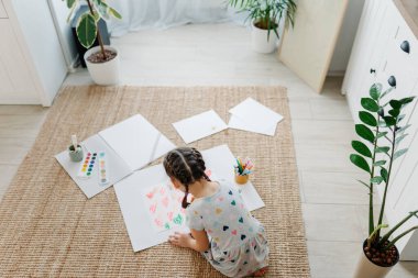 Çocuk bir sürü kalp çiziyor.