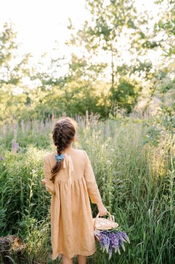 Yaz titreşimleri. Yazın verdiği his. Keten hardal rengi elbiseler giyen, sepet ve lupin çiçekleriyle yolda yürüyen küçük bir kız.