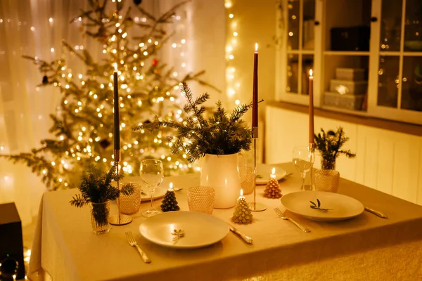 Christmas decorated dining table with dishes, glasses and candles, serving