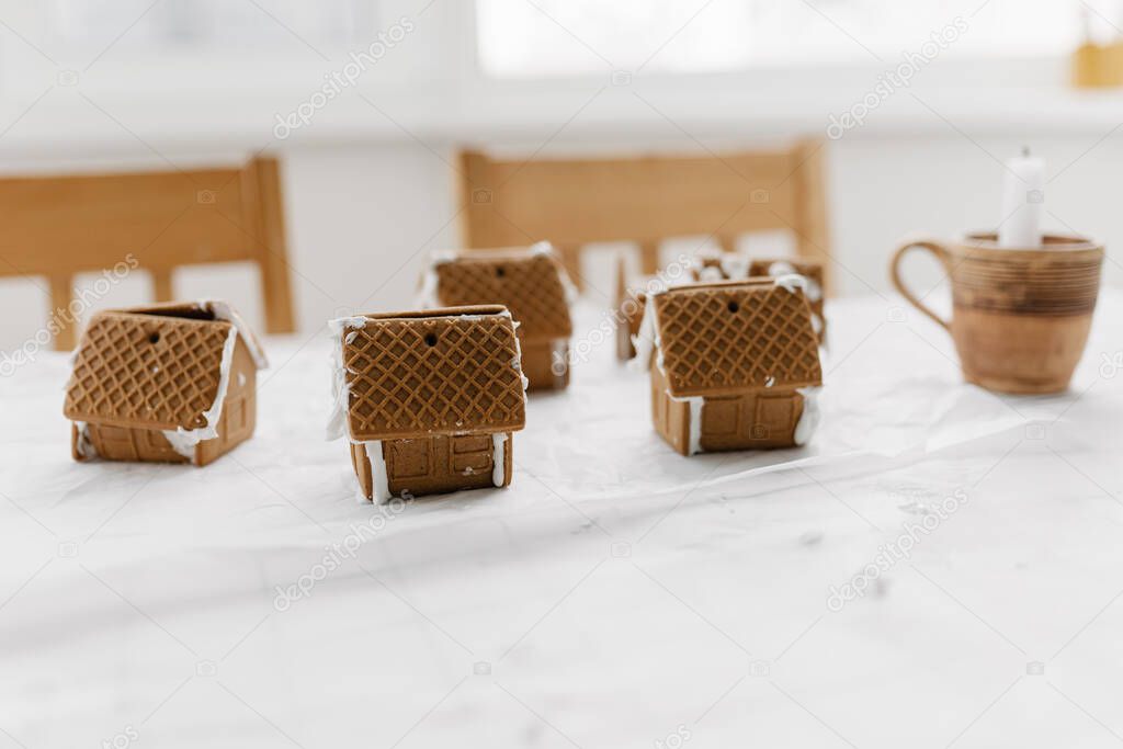 Decorated with icing gingerbread houses on the table. Christmas sweets, popular Christmas decorations. Gingerbread house - classic holiday tradition