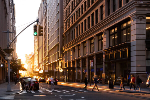 Busy intersection with crowds of people walking through an intersection on 5th Avenue in New York City with summer sunlight shining in the background