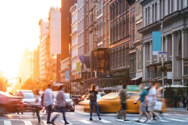 Manhattan 'da 5. Cadde' de kalabalık bir kavşak var. New York 'ta gün batımı binaların arkasında parlıyor.
