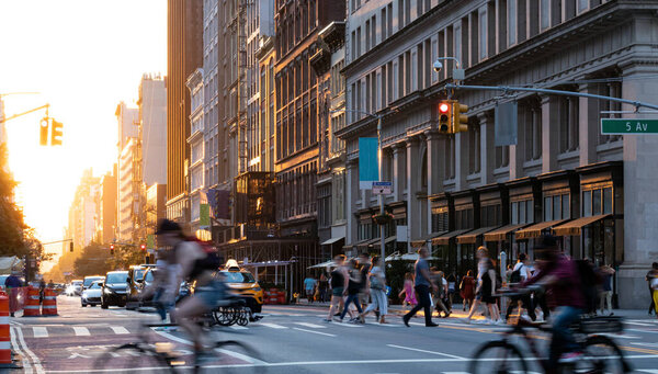 Crowded street scene with people, cars and bikes at the busy intersection of 23rd St and 5th Avenue in Manhattan New York City NYC