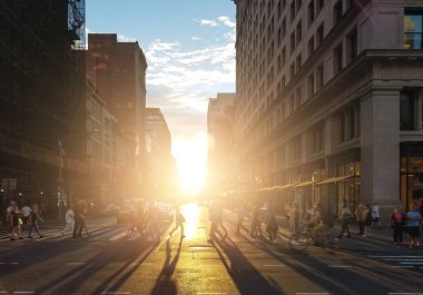 Manhattan 'ın göbeğinde New York' ta kalabalık bir caddeden geçen kalabalığın üzerinde gün ışığı parlıyor.