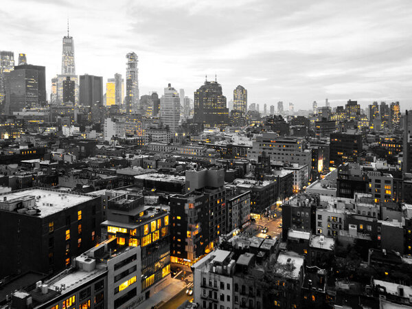 Yellow lights glowing in black and white cityscape of the lower Manhattan skyline in New York City at night