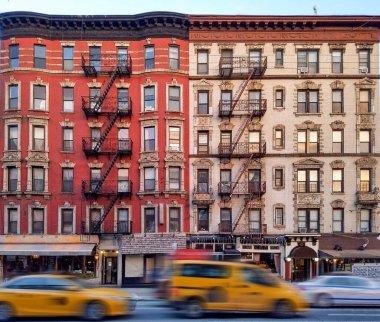 New York 'un East Village semtinde 2. Cadde' deki eski apartman binalarında taksiler caddeden aşağı doğru ilerliyor.