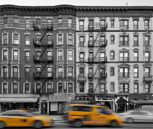 Yellow taxis driving past old apartment buildings in the East Village neighborhood of New York City in black and white