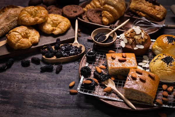 木のテーブルには 新鮮な桑や桑のジャムとパン屋さんや甘いパンの様々な種類 暗い木の板の上に焼きパンの盛り合わせコピースペース — ストック写真