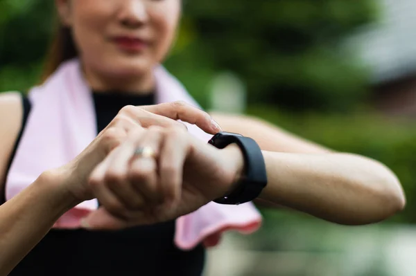 Unrecognizable sporty women in sports wear raise hand and use finger to adjust setting application in smartwatch on wrist to checking result after workout or exercise. Concept of good health care.