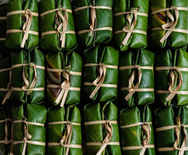 Khao Tom Mud, a popular Thai traditional dessert, made from ripe bananas, glutinous rice, sugar, and coconut milk, wrapped in fresh banana leaves and tied with string made from plant rinds.