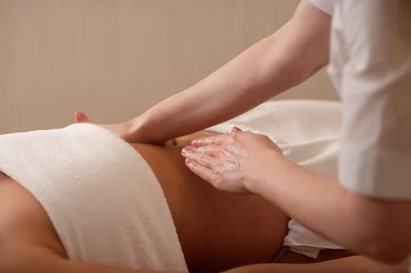 Woman receiving a belly massage at spa salon. Female patient is receiving treatment by professional osteopathy therapis
