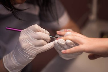 Güzellik salonundaki kadın manikür yaptırıyor. Lear oje ve fırça, makro. Sığ alan derinliği