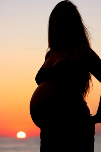 Standng mujer embarazada silueta y salida del sol del océano — Foto de Stock