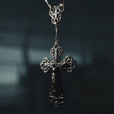 İzole edilmiş karanlık bir arkaplanda asılı eski bir tespih boncuğu kolyesinin yakın çekimi.