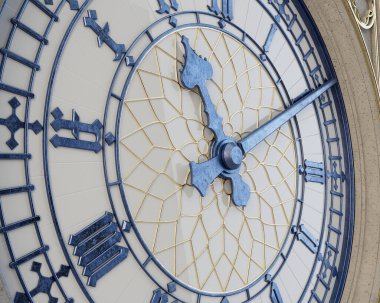 Beton, altın ve demirden yapılmış, izole edilmiş bir stüdyo arka planında beyaz cam destekli süslü bir antika kule saati.